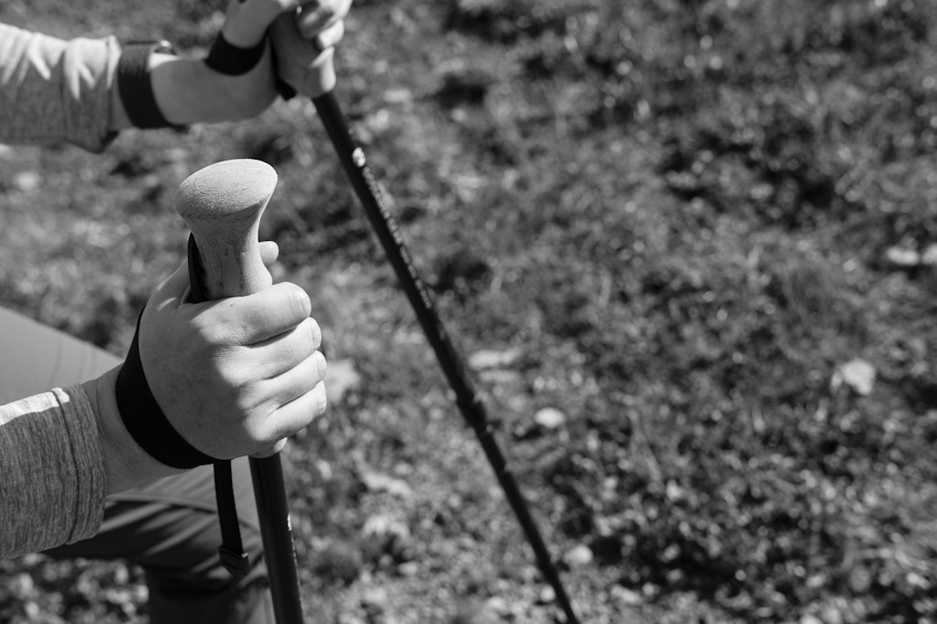 detail of a person using hiking poles on a trial