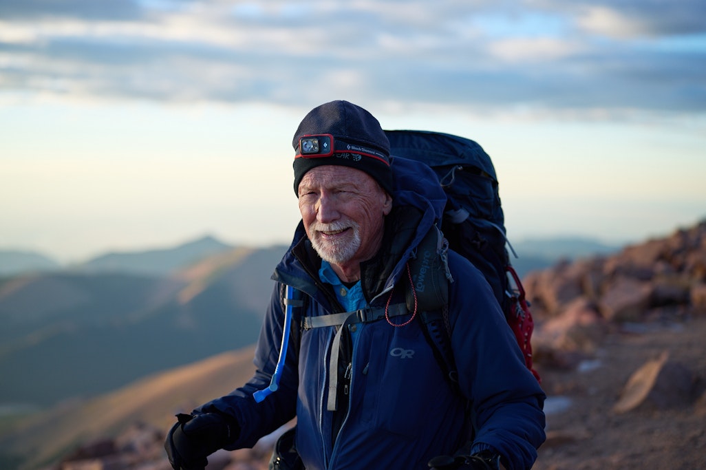 a portrait of hiker in early morning light on top of a mountain
