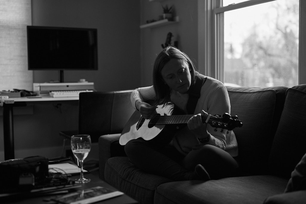sunlit monochrome scene: a person playing guitar in a living room
