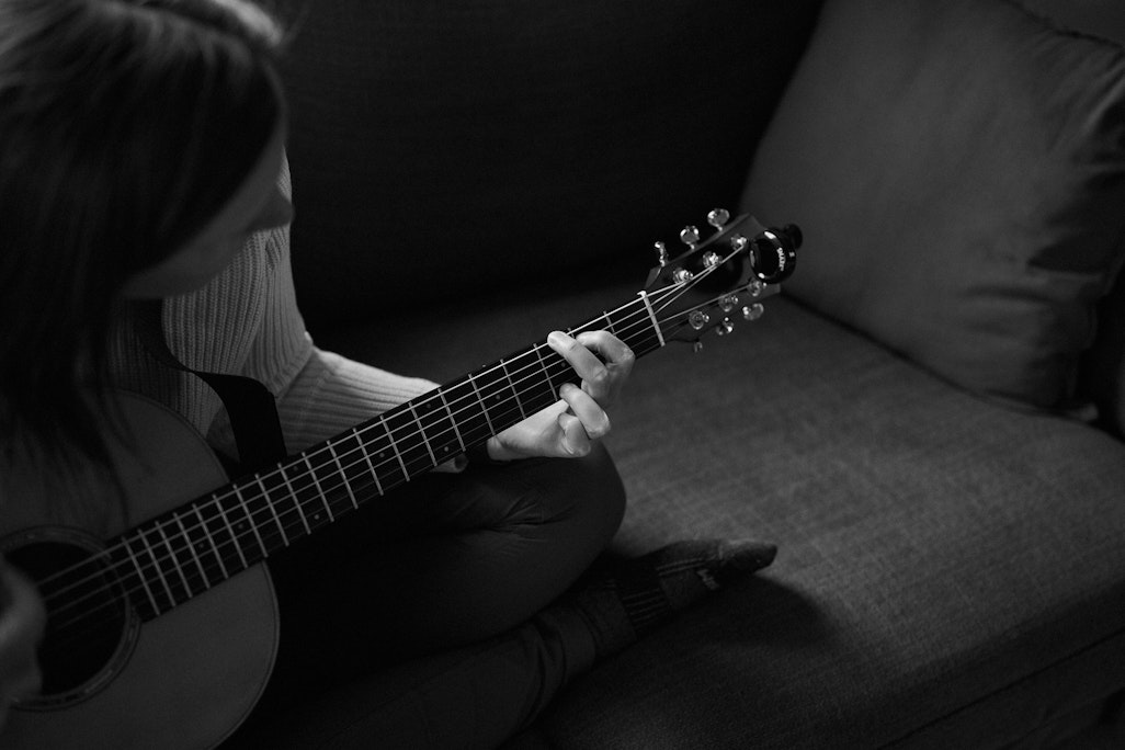 close up of a person playing an acoustic guitar in a living room