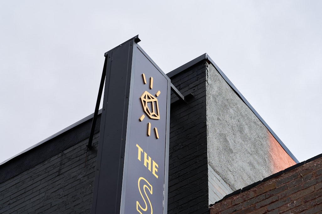 sign for The Sluice in Old Colorado City, yellow logo on a dark sign