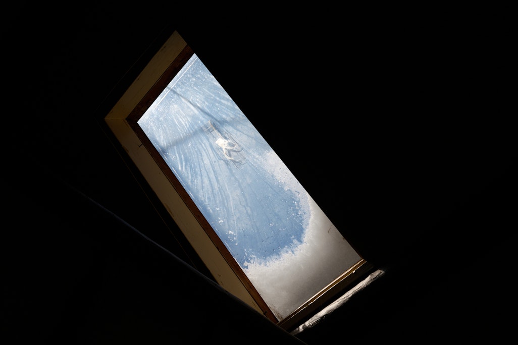 an interior window on a slanted roof in Barr Camp, piled with snow, dark room