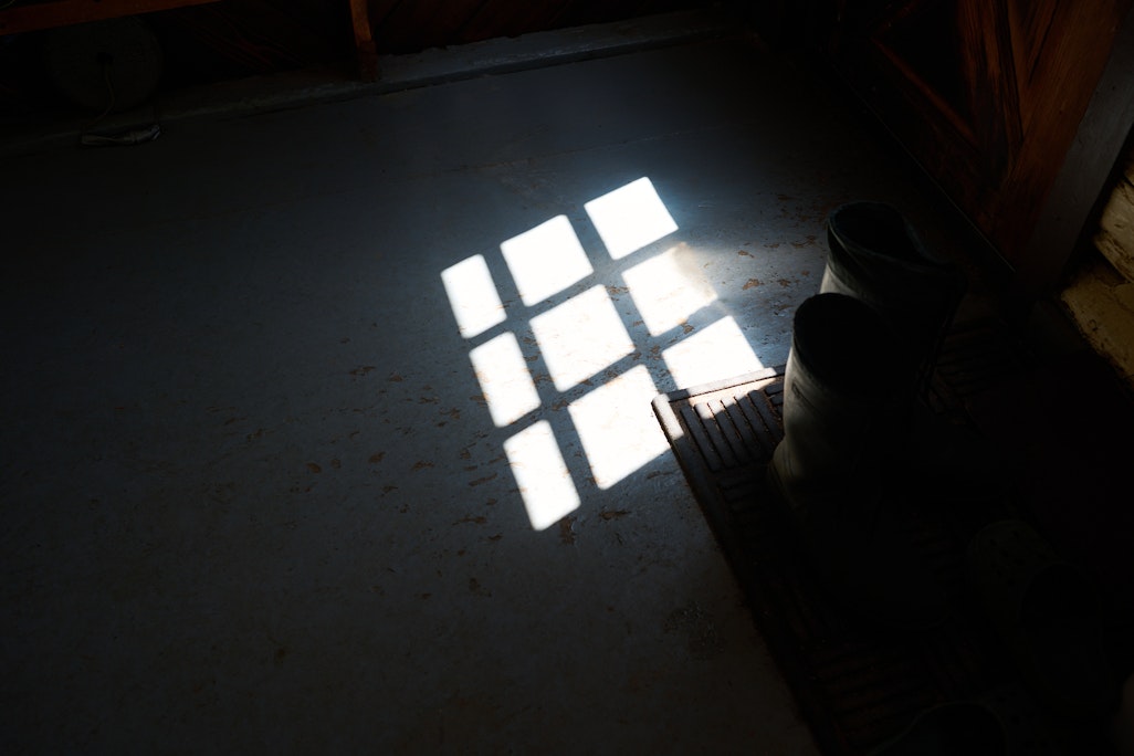 sun shining through paned glass of the door to the dark interior of Barr Camp cabin