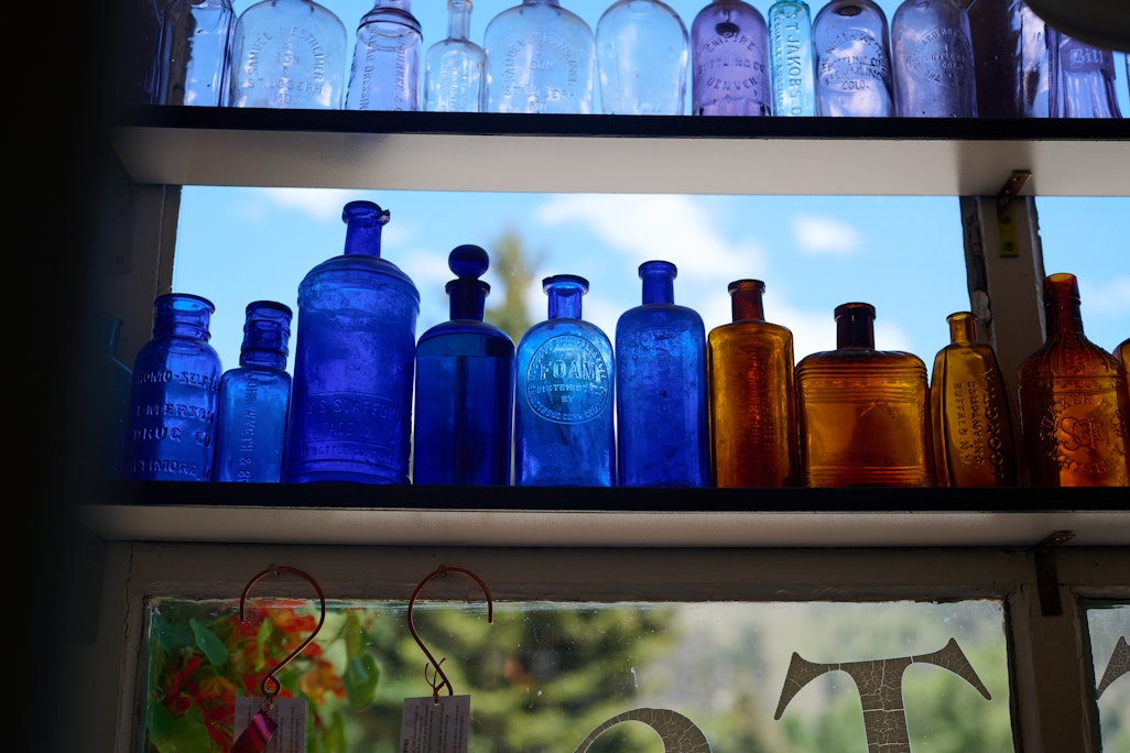 colored vintage bottles in a store front in Lake City, sun shining through the window