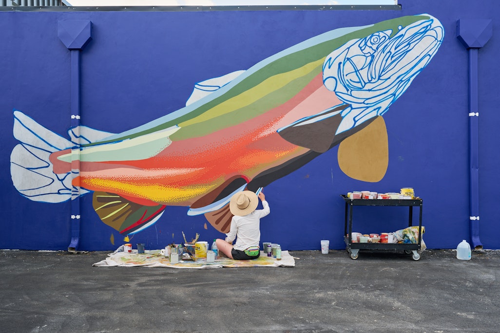 wide view of a mural in progress by Molly McClure, a brook trout on a blue background
