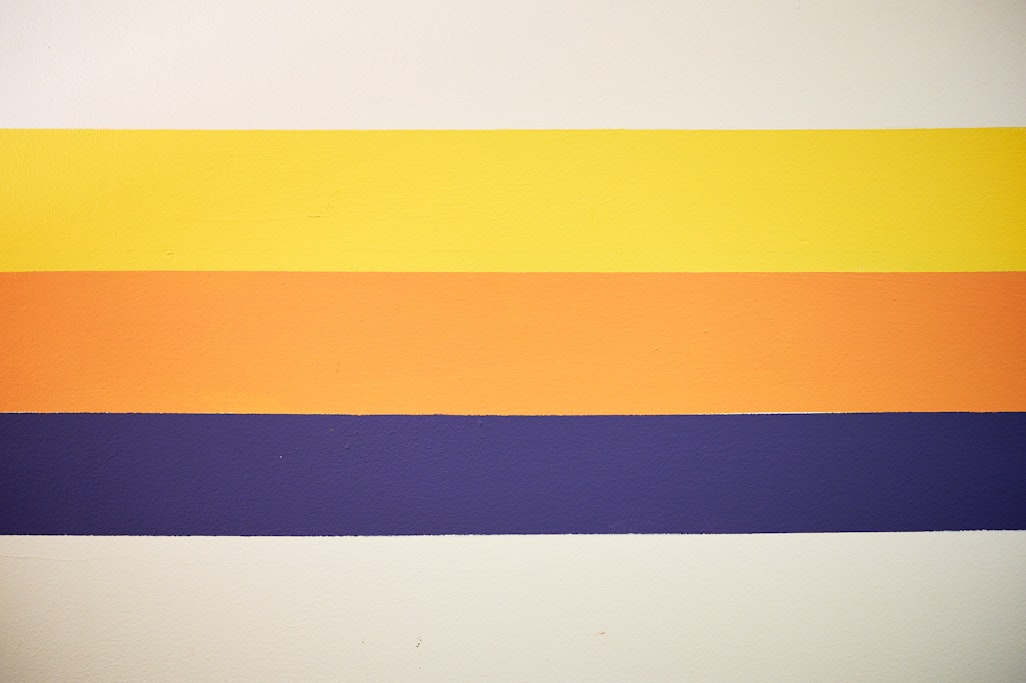 three colors painted on a wall at Groovy print shop: yellow, orange, and purple