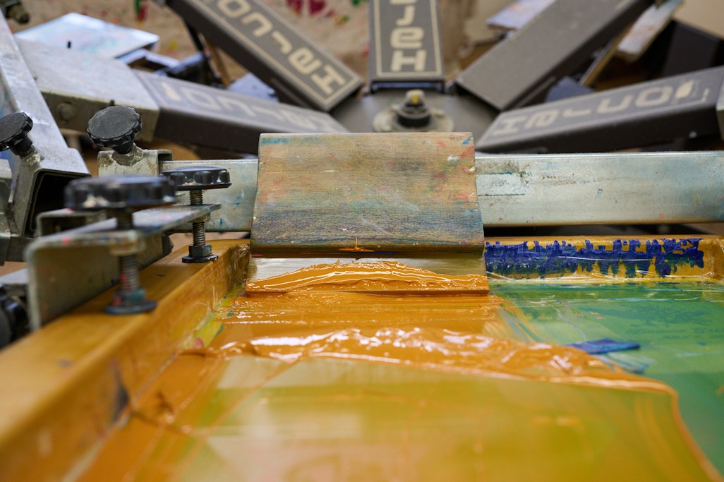 bold orange paint on a screen print press, ready to be used