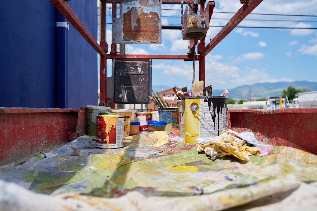 painting materials, on a platform for a large-scale mural painting, mountains and sky in the background