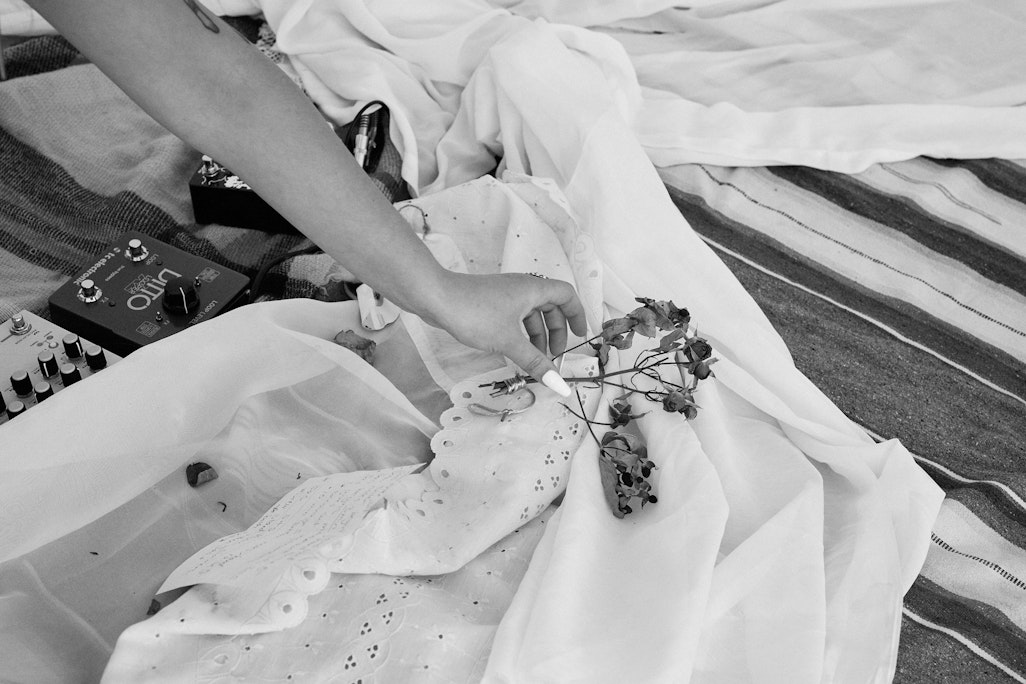 a person’s hand placing dried flowers on white cloth as a part of a decoration for a performance, monochromatic