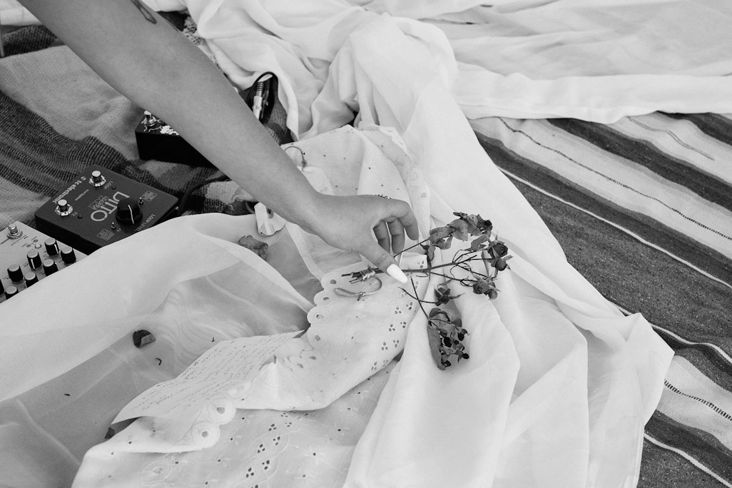 a person’s hand placing dried flowers on white cloth as a part of a decoration for a performance, monochromatic