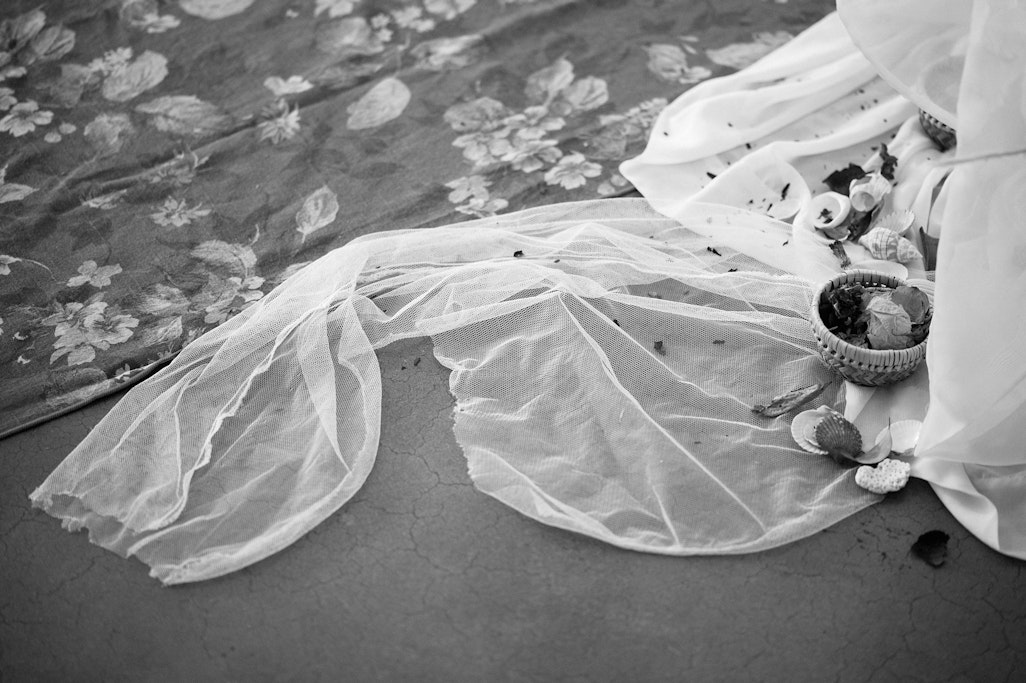 white cloth and dried flowers next to a rug in a performing arts space, monochrome detail