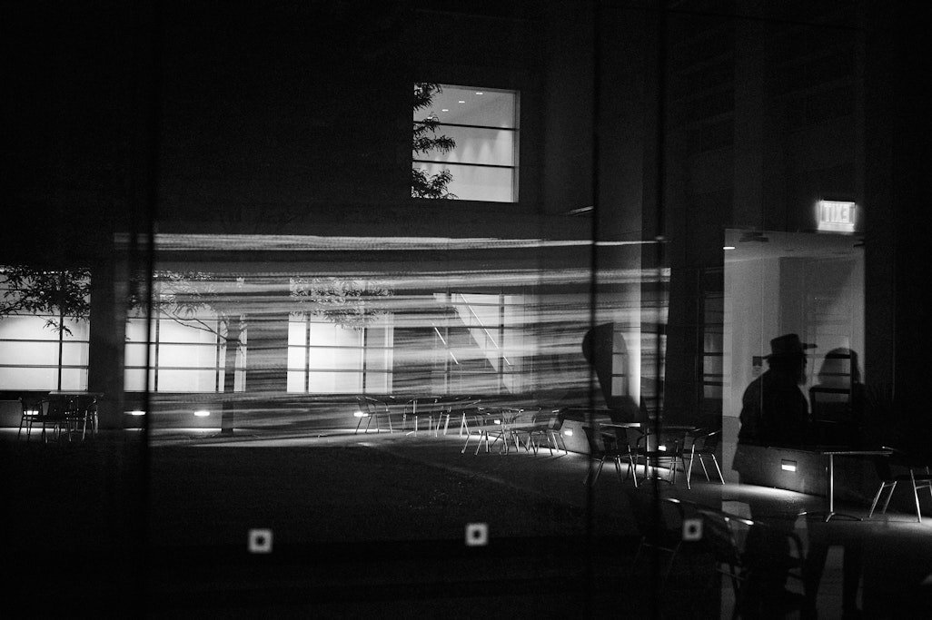 a bright projector reflecting into the courtyard at Fine Arts Center, dark night in monochrome